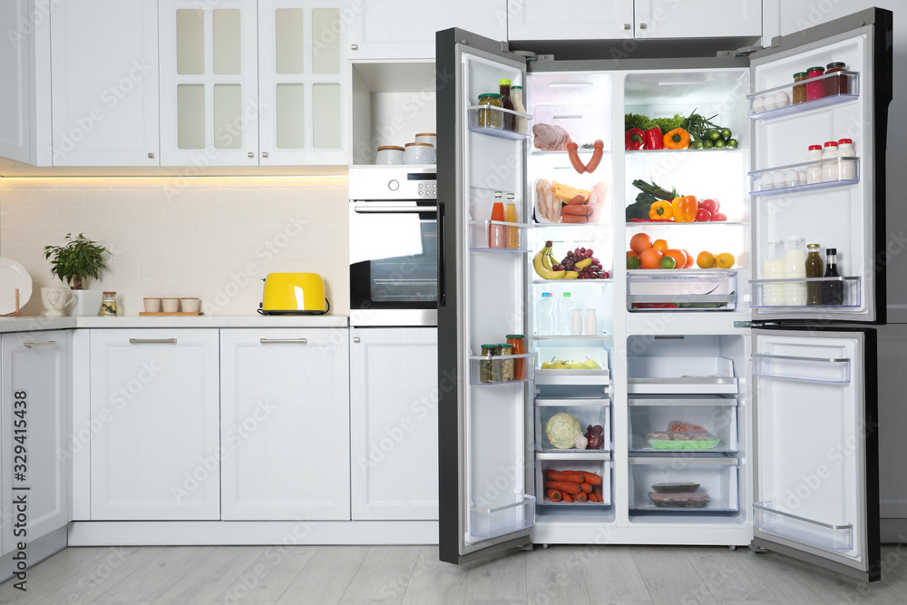 Open refrigerator filled with food in kitchen Open refrigerator filled with food in kitchen