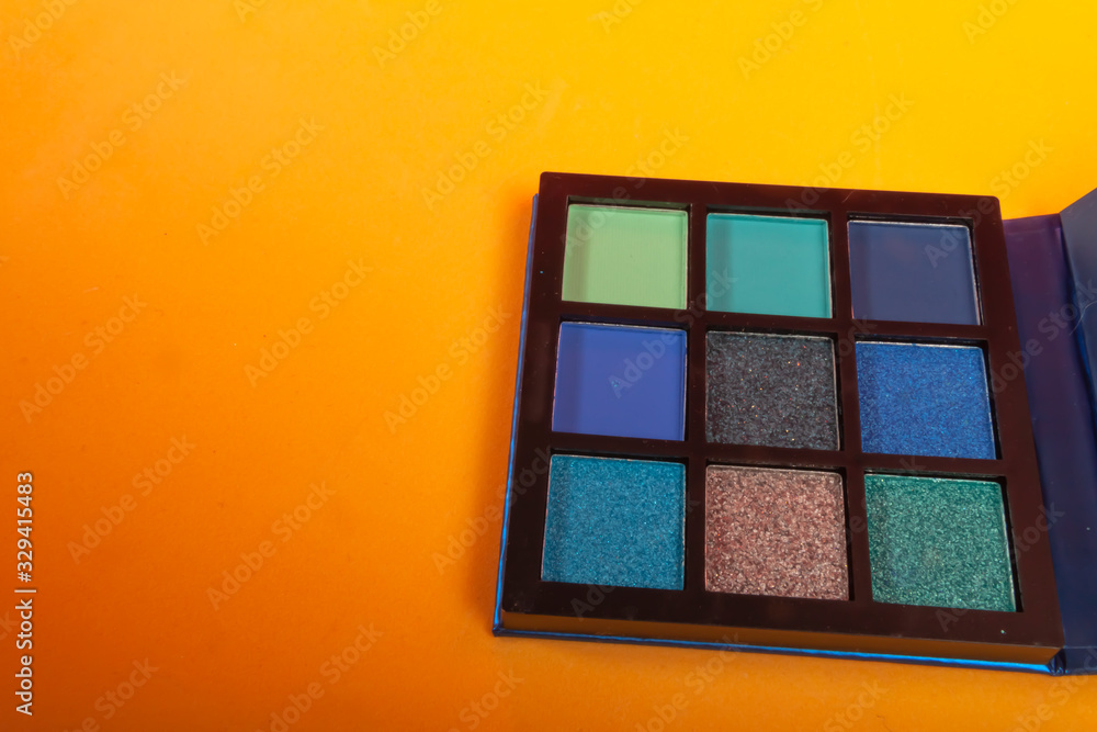 Fototapeta premium Eye shadow palette with blue colors on yellow background. Make up concept. Copy space image for your text