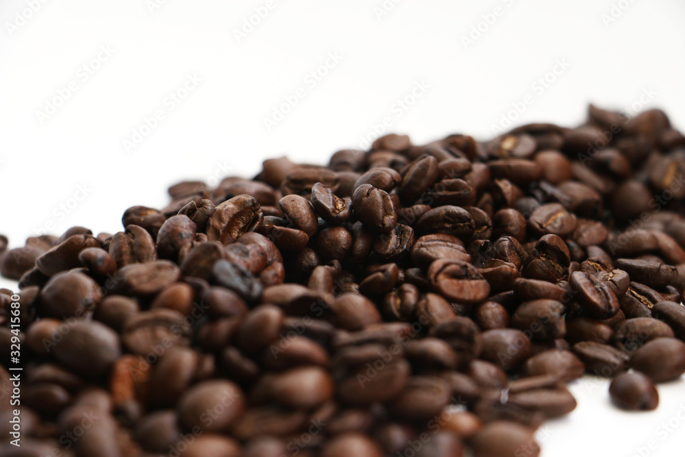 An isolated pile of roasted coffee beans on a white background surface An isolated pile of roasted coffee beans on a white background surface