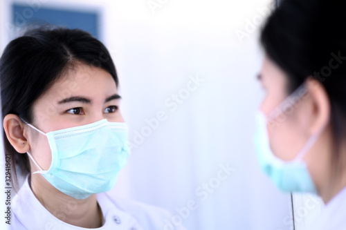 Female dentist wearing surgical mask looking in the mirror