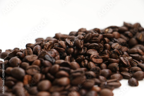 An isolated pile of roasted coffee beans on a white background surface