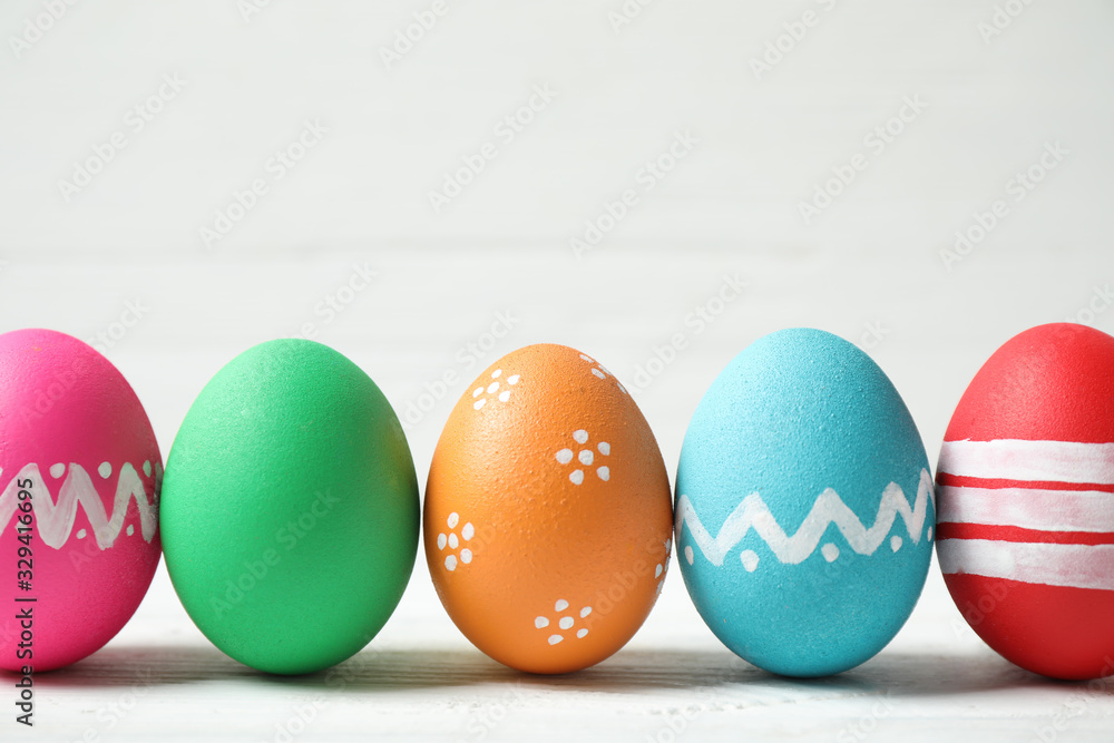 Colorful Easter eggs on white wooden background. Space for text