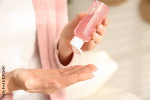 Woman applying antiseptic gel at home  closeup