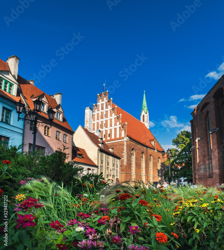 St John Church in Old Town of Riga, Latvia. Beautiful flowers in foreground and aged Latvian lutheran Church under blue sky