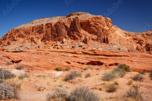 Mountains surrounding Fire wave during wonderful sunny day with blue sky, in Valley of Fire State Park, Nevada, USA