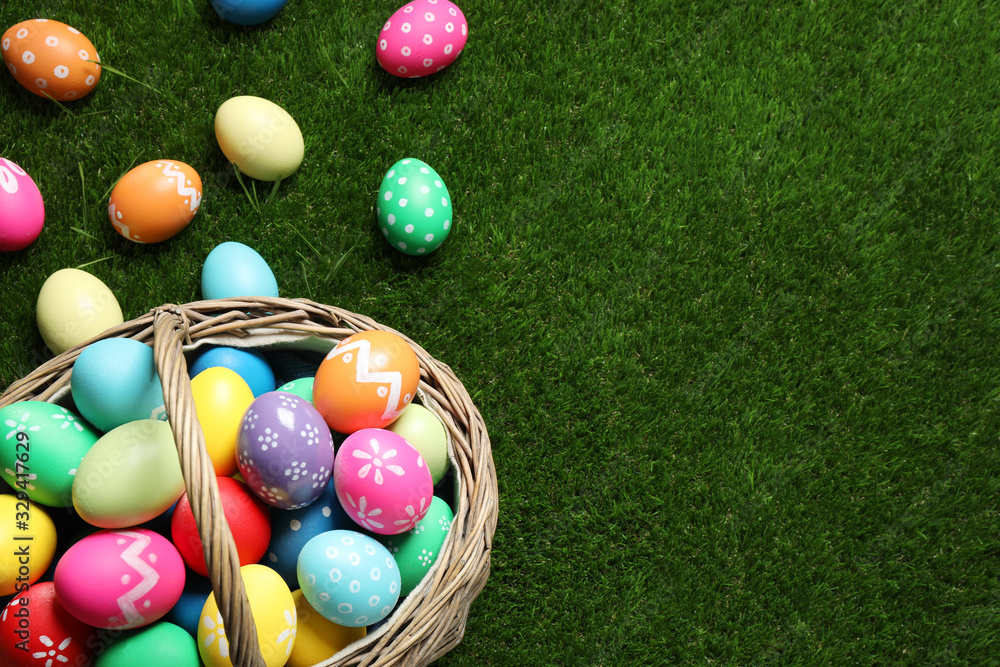 Colorful Easter eggs in basket on green grass, above view. Space for text Colorful Easter eggs in basket on green grass, above view. Space for text