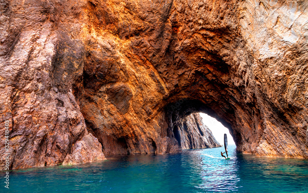 Beaches and grottoes Palmarola's island, Ponza, Italy. Windsurfing sailing under the rock arch.