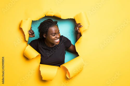 Young smile african woman posing from yellow paper hole © F8  \ Suport Ukraine