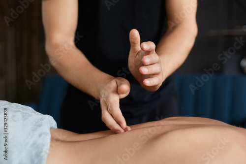 Young beautiful woman enjoying back and shouders massage in spa.Professional massage therapist is treating a female patient in apartment.Relaxation,beauty,body and face treatment concept.Home massage.