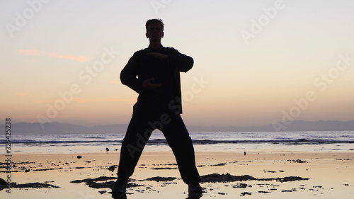 Silhouette man practices qigong exercises, working with qi energy, stand shallow.
