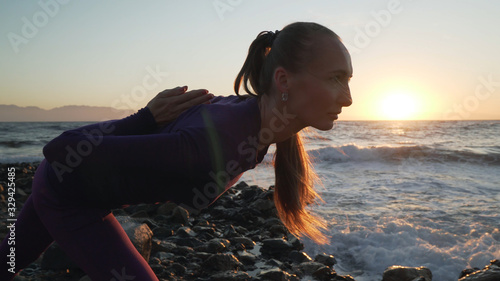 Flexible caucasian girl practice yoga pose at morning seashore. photo