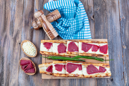 Turkish name; Pastirmali Kasar peynirli pide. Turkish style pide with long roasted and pastrami pita. Baked in stone oven with cheddar cheese. photo