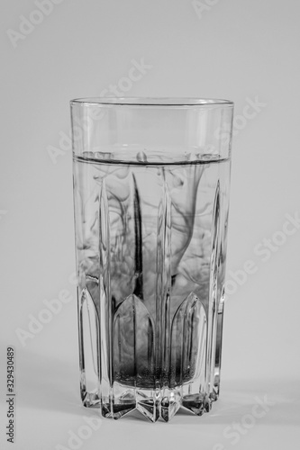 Water pollution concept. Dark substance mixing with clean water in a glass in white background photo