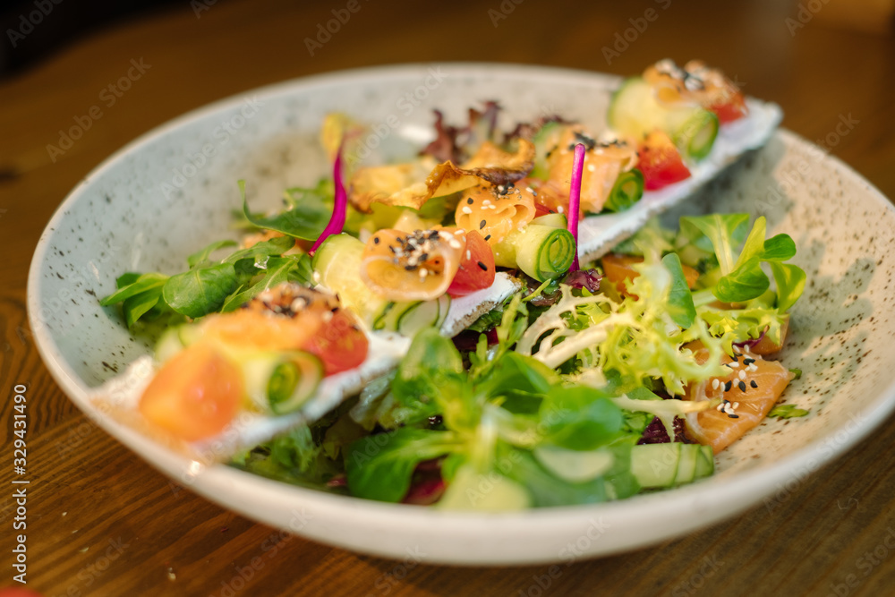 Salad with tuna and greens in white plate on wooden table Salad with tuna and greens in white plate on wooden table
