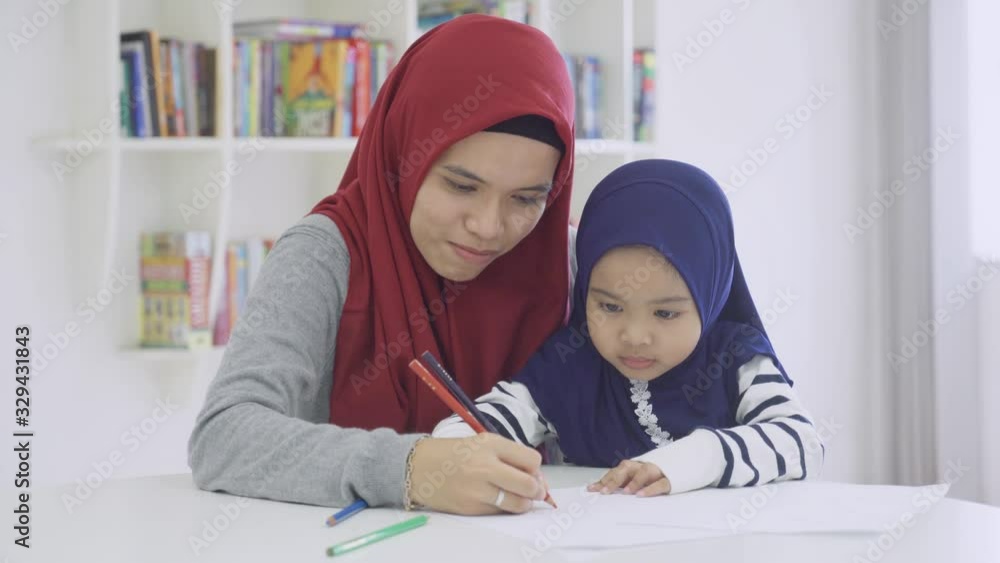 Young muslim woman helping her daughter for drawing on the paper at home. Shot in 4k resolution Young muslim woman helping her daughter for drawing on the paper at home. Shot in 4k resolution