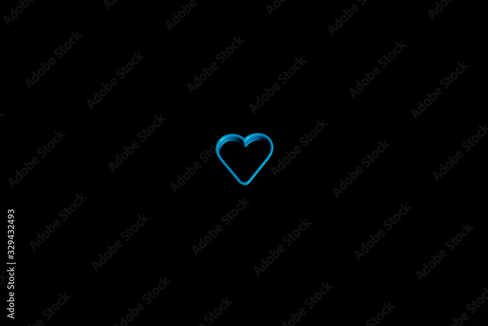 Blue plastic cookie cutter for making cookies in the shape of a heart on a black background. Culinary concept. Flat lay with copyspace. Blue plastic cookie cutter for making cookies in the shape of a heart on a black background. Culinary concept. Flat lay with copyspace.