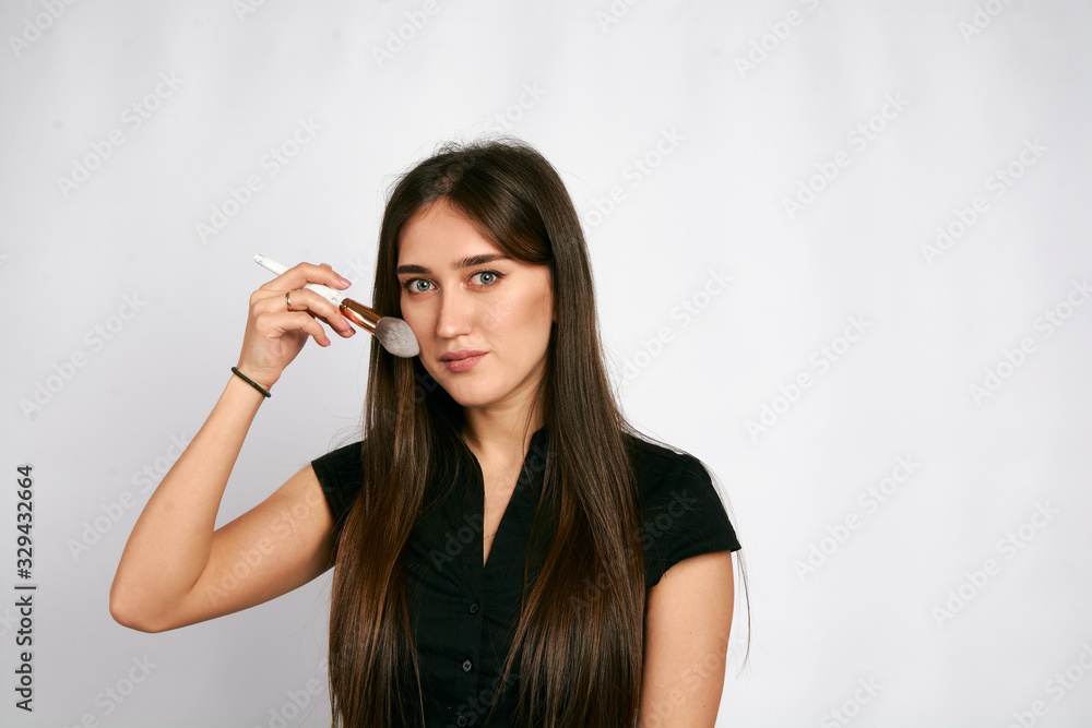 Professional makeup artist poses with the makeup brush and makeup products for advertising on white background. Professional makeup artist poses with the makeup brush and makeup products for advertising on white background.