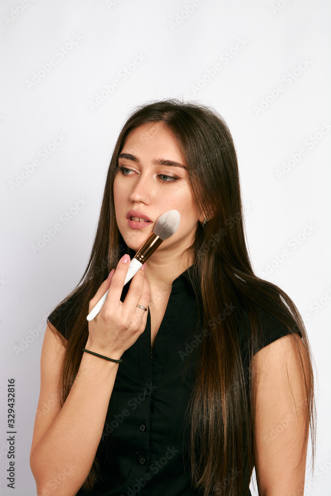 Professional makeup artist poses with the makeup brush and makeup products for advertising on white background. Professional makeup artist poses with the makeup brush and makeup products for advertising on white background.