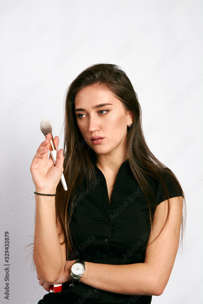 Professional makeup artist poses with the makeup brush and makeup products for advertising on white background. Professional makeup artist poses with the makeup brush and makeup products for advertising on white background.