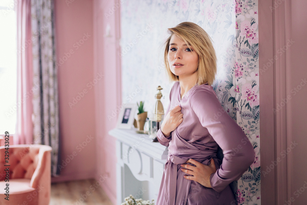 A beautiful young woman standing near the fireplace A beautiful young woman standing near the fireplace