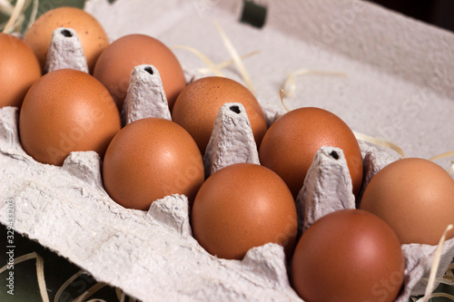 Fresh brown eggs in a special cardboard box (egg tray) decorated with hay. Egg storage concept, preparing for Easter