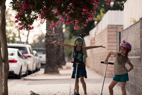 Canvas Print Girls are wearing safety helmets while scootering on the sidewalk of their LA city