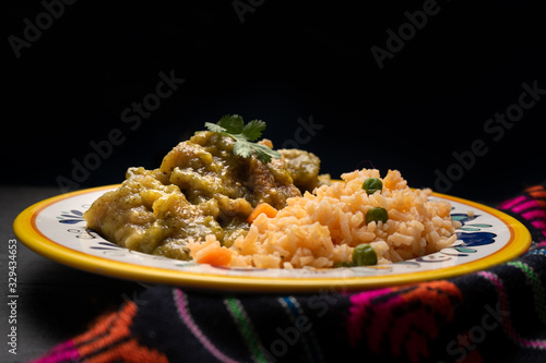 Mexican pork chicharron with green sauce and rice on dark background