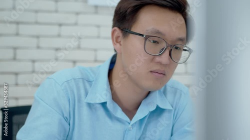 Portrait of Concentred Asian Male Worker using a desktop computer hand typing keyboard, working while sitting at desk.Attractive Businessman doing marketing research, business planning in the office. photo