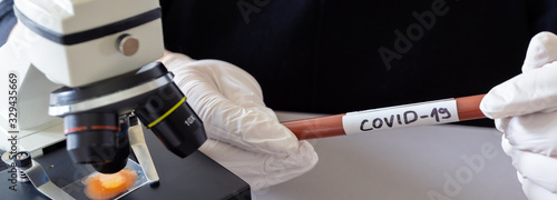 microbiologist with a tube of biological sample contaminated by Coronavirus with label Covid-19 / doctor in the laboratory with a biological tube for analysis and sampling of Covid-19 infectious disea photo