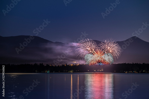Fireworks of celebration and festival in the mountains on the ocean with water reflections at night