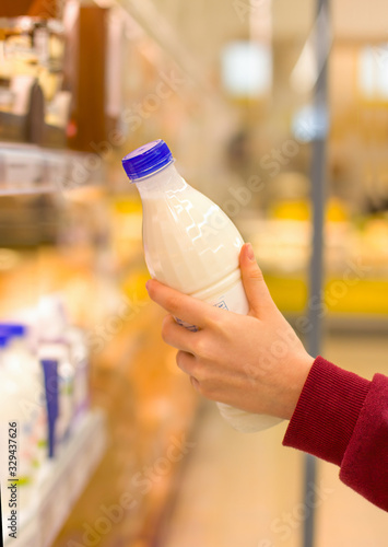 Female hand choosing milk in supermarket. Concept of healthy food, bio, vegetarian, diet.