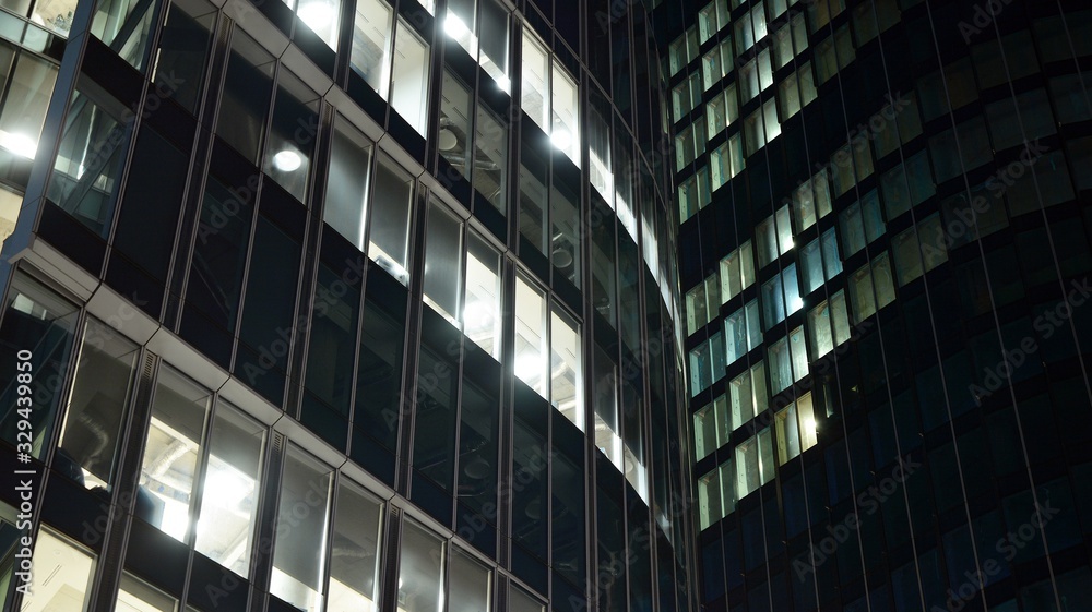 Pattern of office buildings windows illuminated at night. Lighting with Glass architecture facade design with reflection in urban city. Pattern of office buildings windows illuminated at night. Lighting with Glass architecture facade design with reflection in urban city.