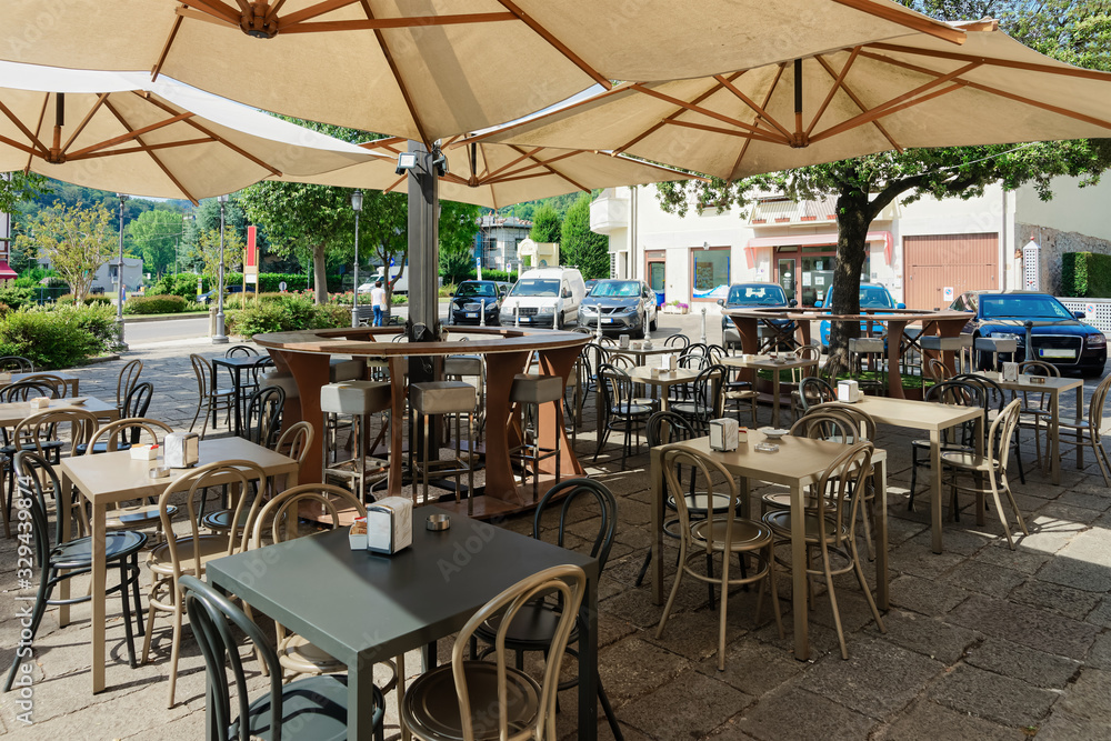Street restaurant with tables and chairs under umbrellas at hotel in Italy