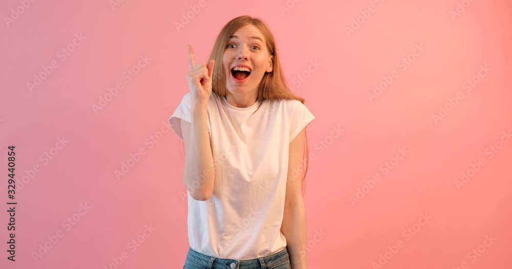 Cheerful girl in a white t-shirt , having fun and happy, on a pink background Cheerful girl in a white t-shirt , having fun and happy, on a pink background