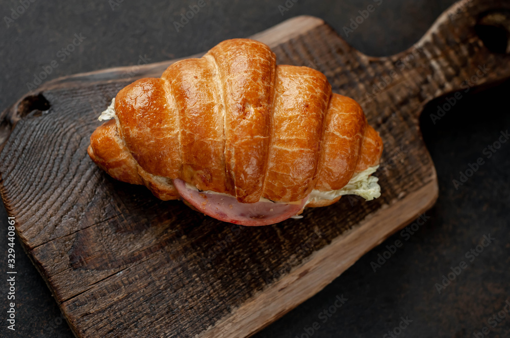 Croissant with sausage, cheese and salad on a stone background Croissant with sausage, cheese and salad on a stone background