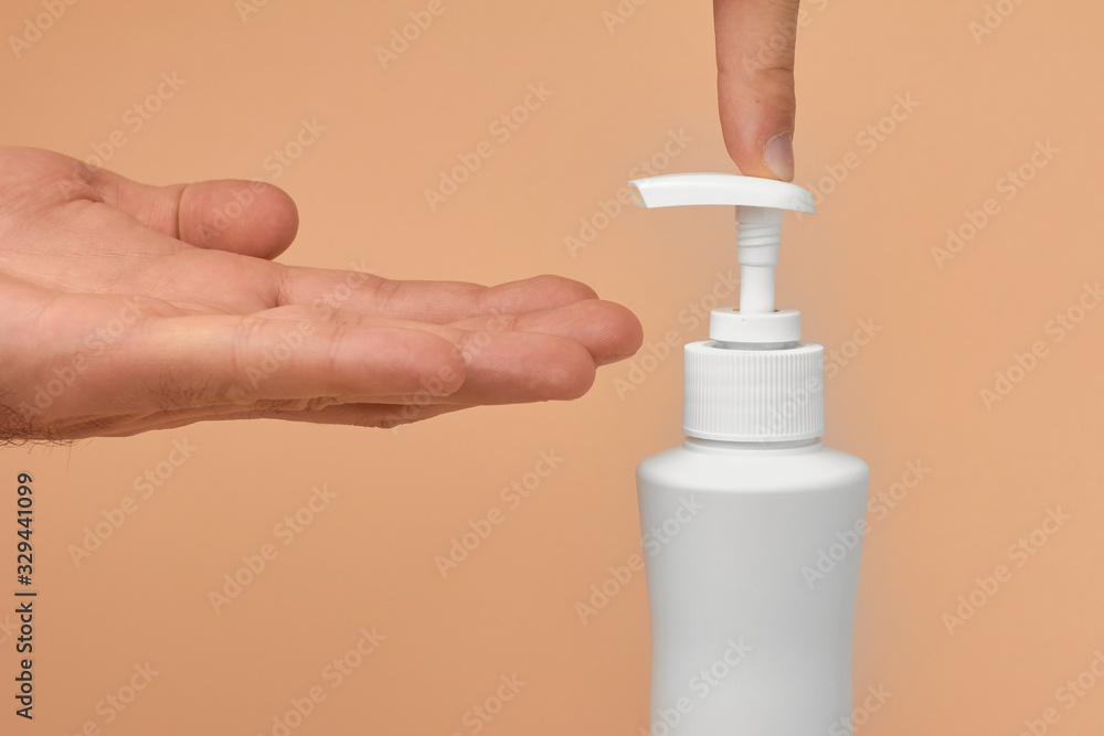 Closeup mans hand using antibacterial liquid soap to protect against COVID-19. Man uses gel for cleaning hands on a blue background. Closeup mans hand using antibacterial liquid soap to protect against COVID-19. Man uses gel for cleaning hands on a blue background.