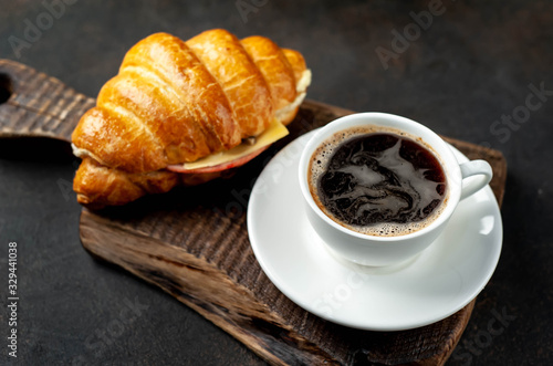 coffee and croissant with sausage, cheese and salad on a stone background. Breakfast concept
