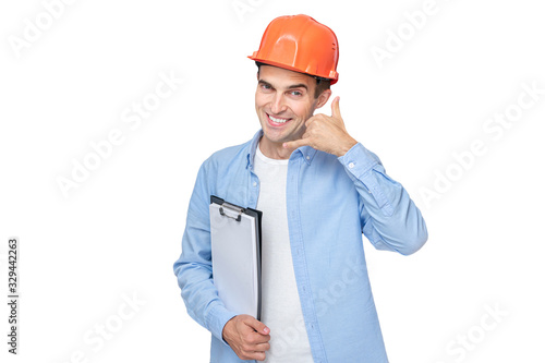 Cuadro en lienzo Cheerful builder in helmet shows call me gesture, isolated background, copy sp