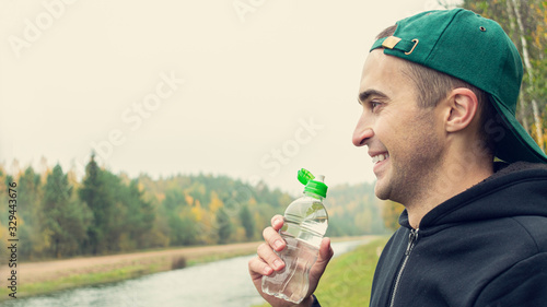 Concept of sports and active lifestyle. Handsome guy with a bottle of water, close up, 16:9
