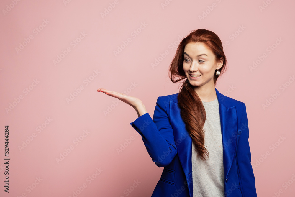 Woman showing pointing on pink background. Very fresh and energetic beautiful young girl smiling happy presenting on pink background Woman showing pointing on pink background. Very fresh and energetic beautiful young girl smiling happy presenting on pink background