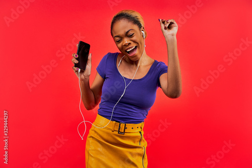 Happy woman in a blue T-shirt and in a yellow skirt with hair gathered in a bun with a phone. Lifestyle concept