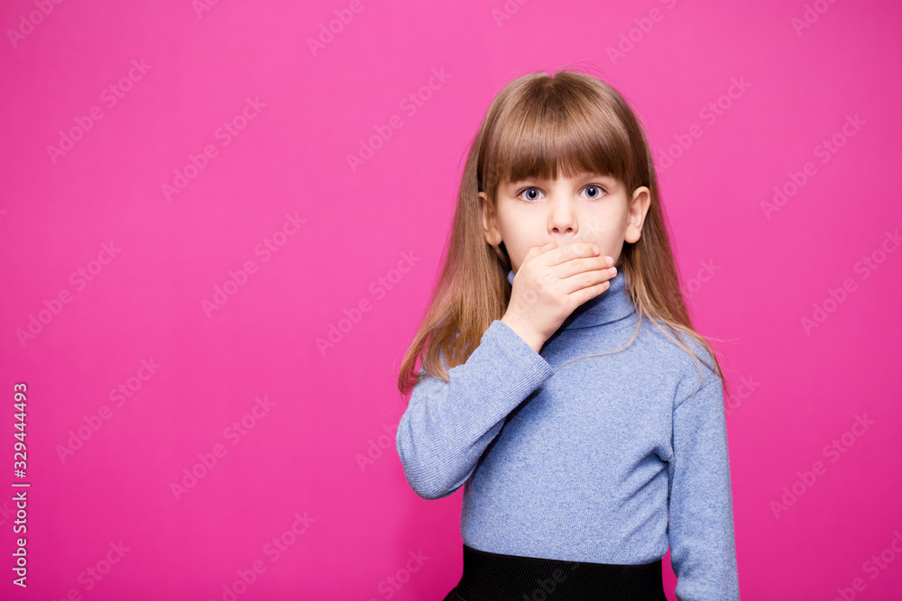 Cute little girl covering her mouth showing intense expression of fear isolated on pink background - obrazy, fototapety, plakaty 