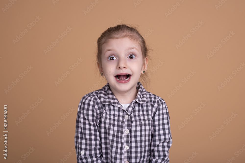 Amazed shocked little girl with open mouth isolated on beige neutral background Amazed shocked little girl with open mouth isolated on beige neutral background