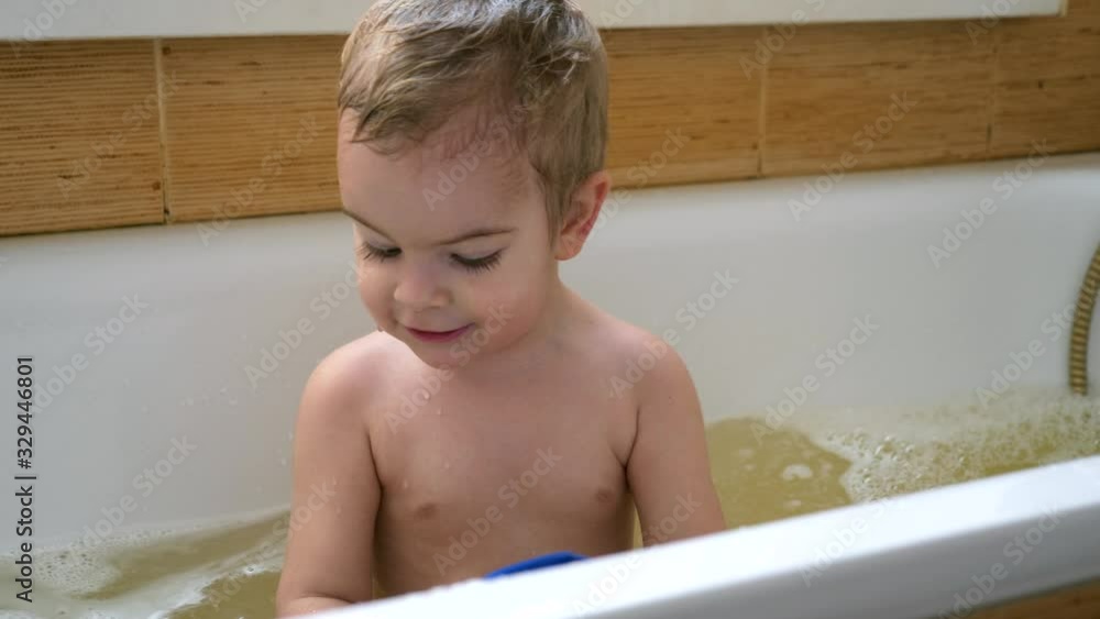 Happy Joyful Child Plays Smiling with Toys in Water In Bathtub. Cute Little Boy Having Fun In Bathroom. Slow motion 0.5 speed 60fps Happy Joyful Child Plays Smiling with Toys in Water In Bathtub. Cute Little Boy Having Fun In Bathroom. Slow motion 0.5 speed 60fps