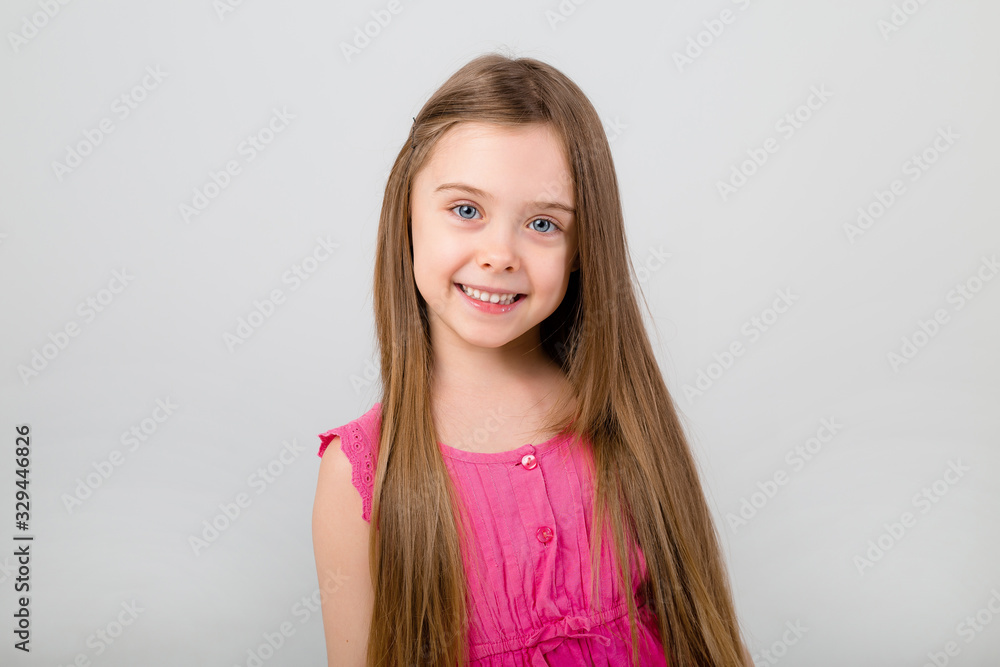 portrait of a little girl with long hair in pink clothes on a white background. happy baby girl smiling on white background isolate portrait of a little girl with long hair in pink clothes on a white background. happy baby girl smiling on white background isolate