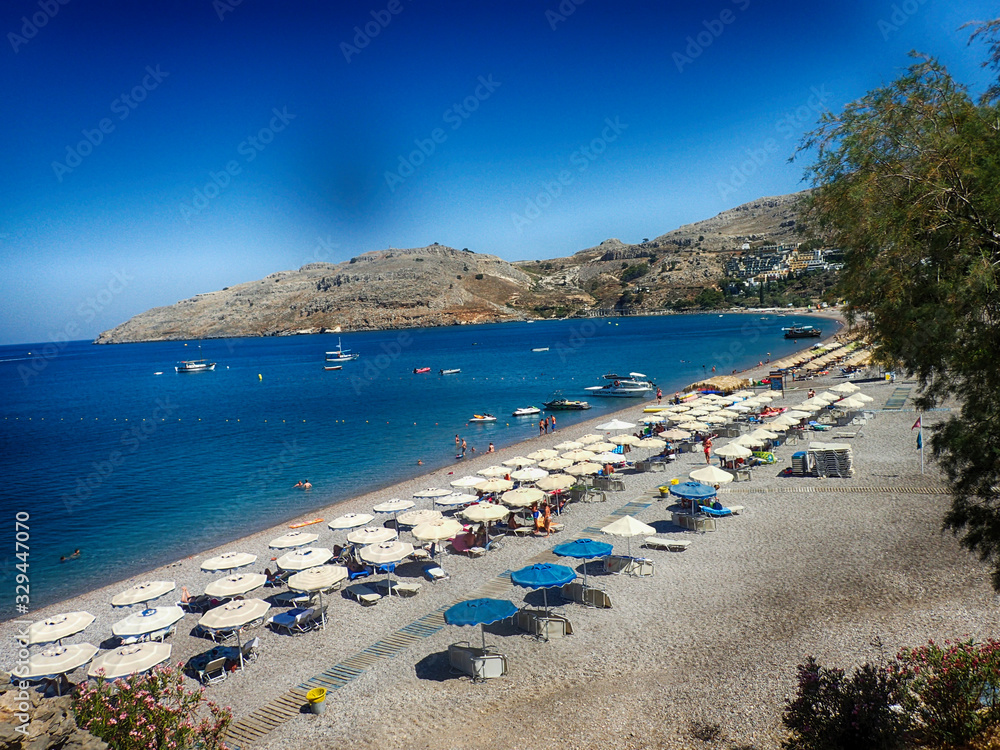  beach on the Greek island of Rhodes with blue water and a strip on a hot summer's vacation day