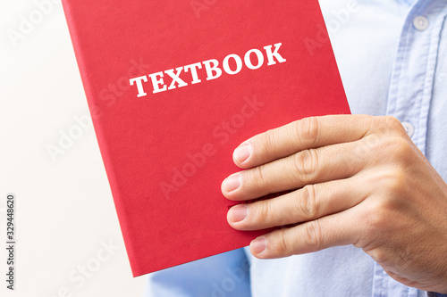 Person shows the tutorial, hand with the red book, closeup, cropped image