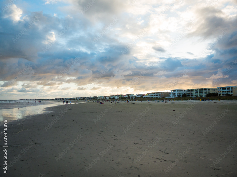 Dramatic cloudscape with sun setting above lively Georgia beach