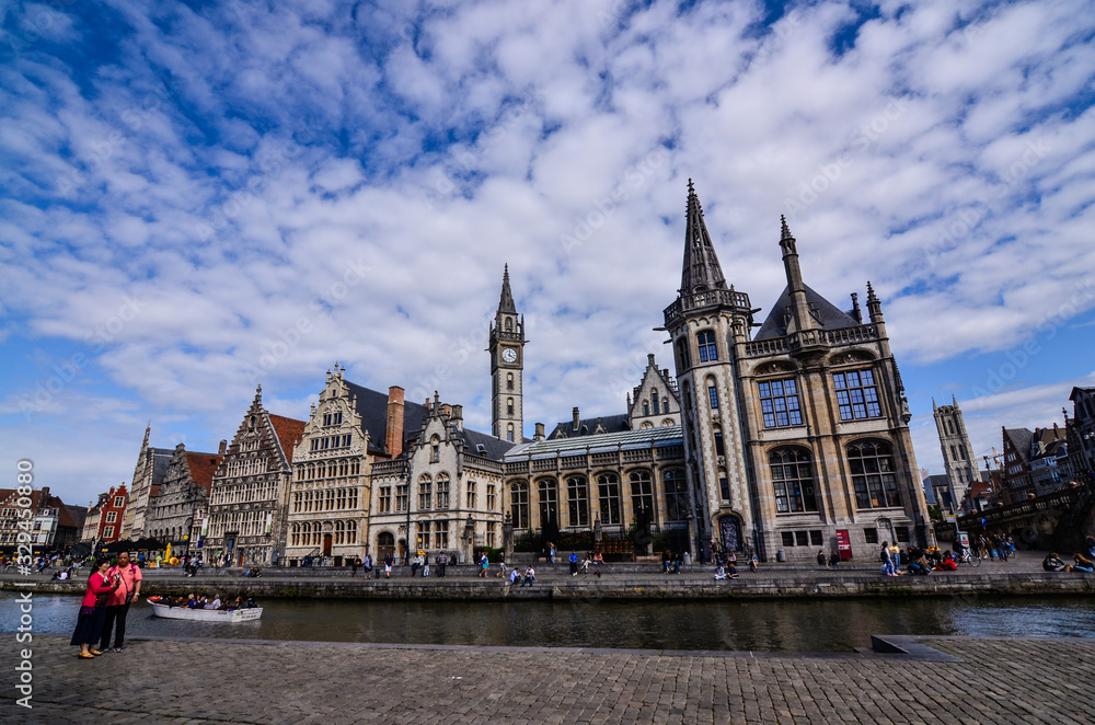 Fototapeta premium Ghent, Belgium, August 2019. Breathtaking cityscape: from the St. Michael bridge along the Graslei canal. One of the most beautiful postcards in the city. On the left a couple stopped to admire.