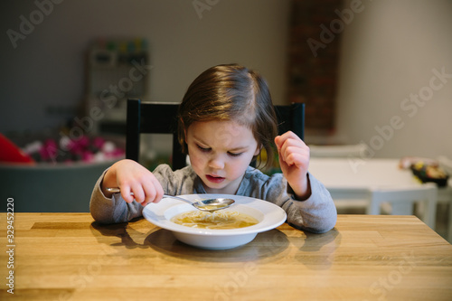Little girl with a bowl of pasta soup